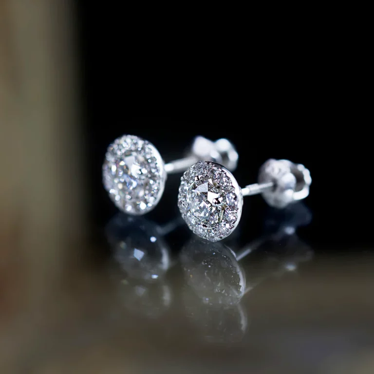 round diamond stud earrings in white gold on the black reflective surface